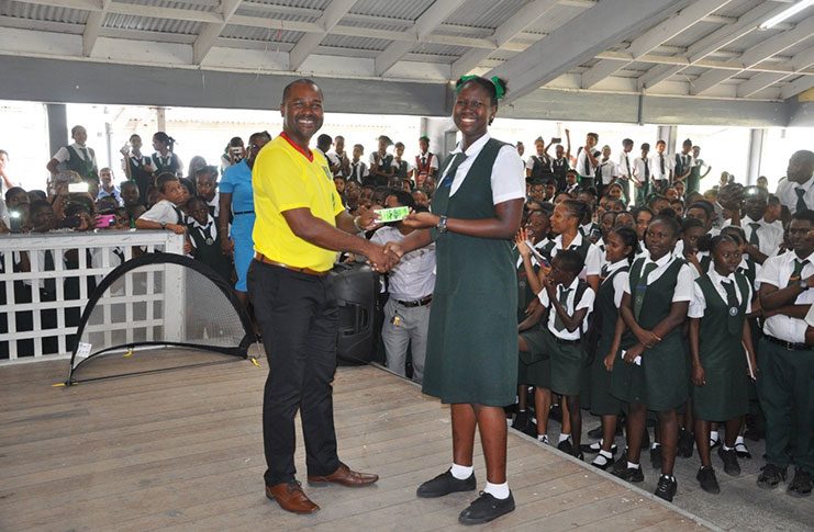 A student of the West Demerara Secondary School receives a match ticket as part of the 'Roar to Gold Cup' campaign.