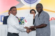The Permanent Secretary of the Ministry of Housing and Water, Bishram Kuppen, hands over the certificate of title to Mr. Julian Success at the Dream Realised Housing Drive held at the Arthur Chung Centre.