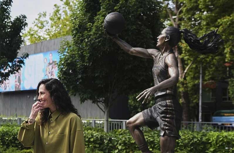 Former Seattle Storm point guard Sue Bird stands near her statue after its unveiling outside Climate Pledge Arena, Sunday in Seattle