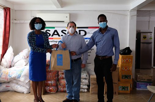 UNDP Resident Representative, Jairo Valverde hands over food items to National AIDS Programme Secretariat Director, Dr. Rhonda Moore and SASOD Managing Director, Joel Simpson