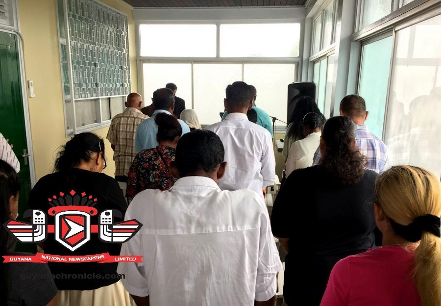 Minister of Public Security ,Khemraj Ramjattan (partly hidden) and relatives of the fishermen observe a minute's silence prior to a meeting at Guyana's embassy in Suriname on Sunday.