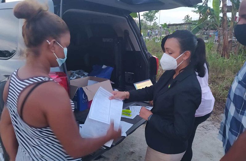 Minister within the Ministry of Housing and Water assists a squatter at Sarah Johanna, East Bank Demerara to apply for a house lot.  (DPI photo)