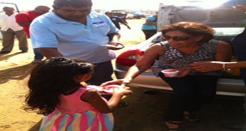 The First Lady offers a cup of delicious ice cream to a little girl at the Easter Sunday Gymkhana
