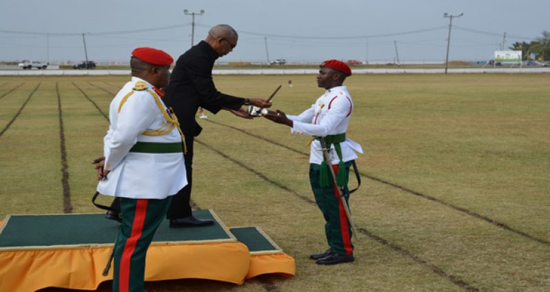 Commander-in-Chief of the Armed Forces, David Granger hands over the award of the sword of honour to Best Graduating student Cleveroy Patrick during the parade