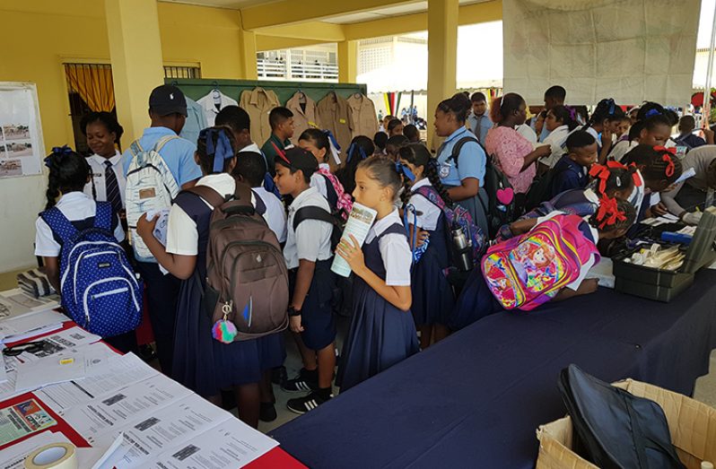 A group of children inspecting items at the Guyana Police Force booth
