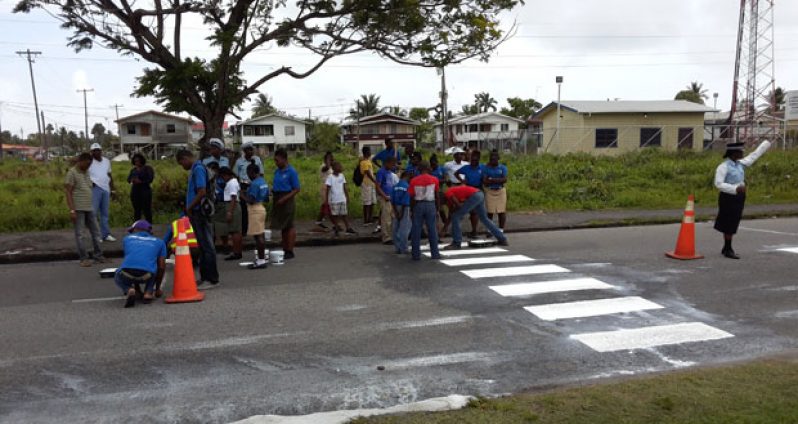 A police traffic rank (extreme right) held the traffic at bay while the young people painted a section of the zebra crossing