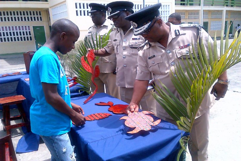 Former Police Commissioner Leroy Brumell and the late Assistant Commissioner Deryck Josiah inspect craft work done by one of the young campers in Essequibo last year.