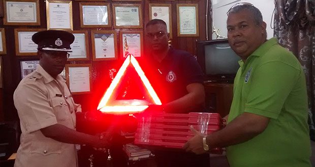 Commander Hicken accepting a caution reflector from R.C Persaud (centre) with help from a member of the SMC