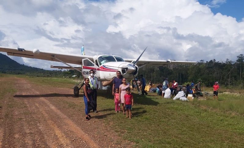 A Trans Guyana pilot stands alongside Region 8 residents following a flight on Friday.(TGA photo)