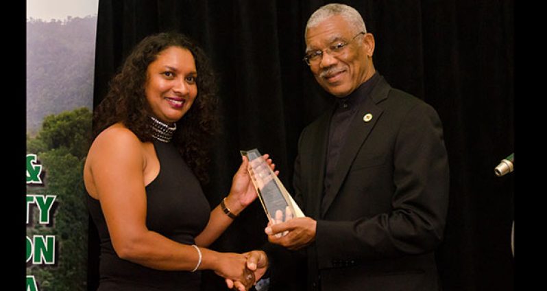 President David Granger presents an award to Terri O'Brien, a representative of Wilderness Explorers after the company’s principal Tony Thorne , who is based in Australia, was inducted into the tourism hall of fame.