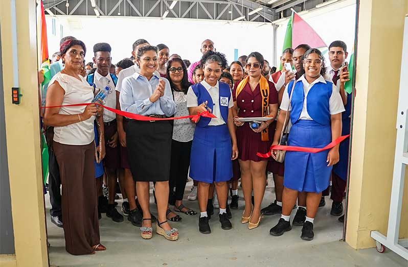 Minister of Education, Priya Manickchand, flanked by students and teachers, observes the formal ribbon cutting ceremony to commission the brand-new Practical Instruction Department (PID) at Bartica Secondary School