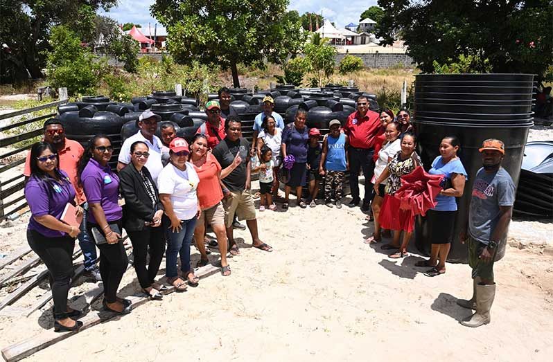 Minister of Housing and Water, Collin Croal, with some of the residents that received the tanks to assist with their household water storage needs