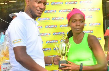 COURTS Marketing Manager Pernell Cummings presents Euleen Josiah-Tanner with her trophy after winning her fourth successive 10K Road Race.
(Adrian Narine Photos)