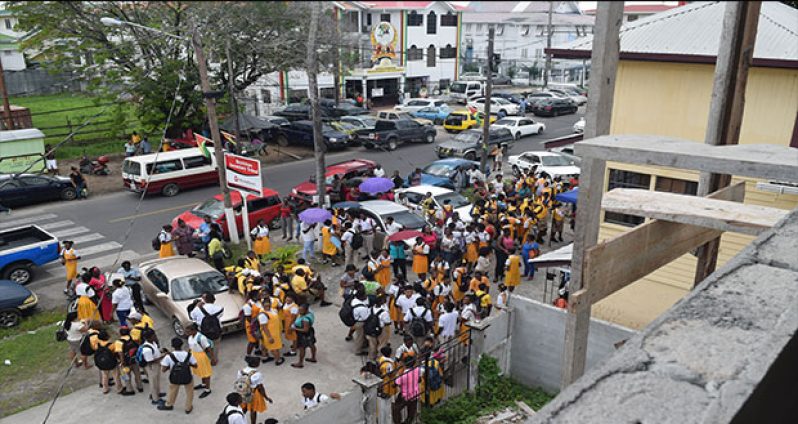 Scores of students, teachers and parents awaiting a final decision from the Ministry of Education in front of the run down Brickdam Secondary School. [Cullen Nelson photo]