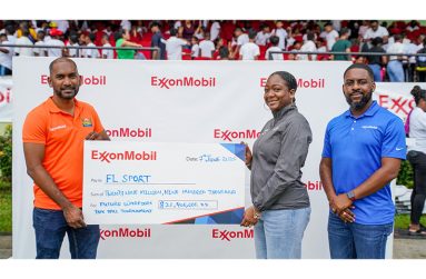 Operations Integrity Management System Coordinator at ExxonMobil Guyana, Tenesha Les Flores, makes a ceremonial presentation to FL Sport's Yusuf Ali in the presence of ExxonMobil Guyana’s Community Relations Supervisor, Ryan Hoppie at the National Stadium, Providence on Saturday