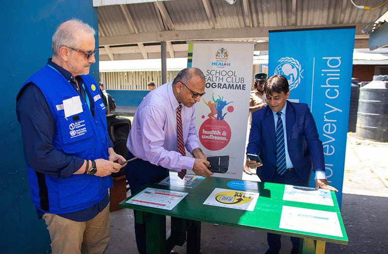 Minister of Health Dr. Frank Anthony along with Deputy Representative of UNICEF Guyana and Suriname, Mr. Irfan Akhtar scan the bar code on the ‘Let’s Talk Green Bench’ that was installed in 25 schools across Guyana