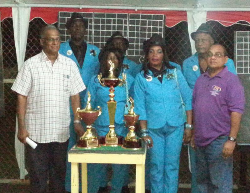 Director of Sport, Neil Kumar (left), and Chief Executive Officer (CEO) of F&H Printing Establishment, Fazil Hakh (right), strikes a pose with the victorious Thunder team after the march past and opening ceremony, while the championship trophies are on display forefront