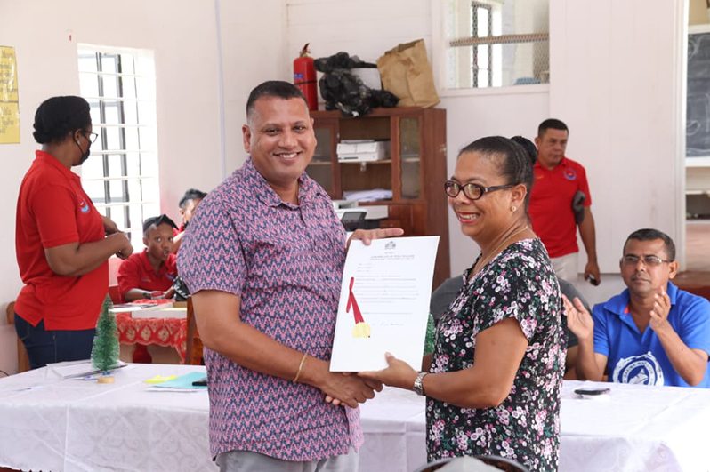Minister of Housing and Water Collin Croal hands over a Land Title to one of the residents