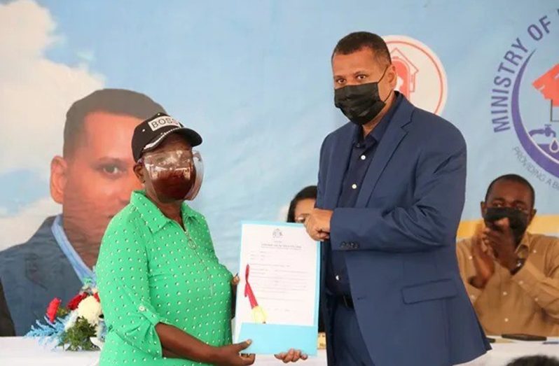 Minister of Housing and Water Collin Croal handing over Certificate of Title to a beneficiary back in July 2021