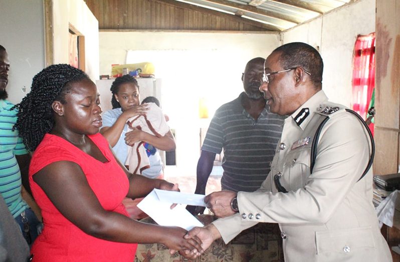 Commissioner of Police (ag), Clifton Hicken, presents a monetary gift to Mrs McPherson on behalf of his family