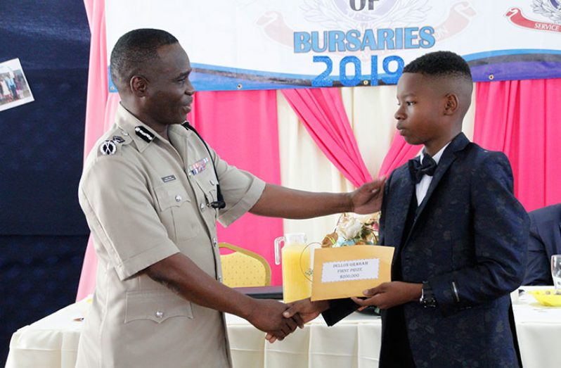 Commissioner of Police, Leslie James handing over a bursary award to the top student of the GPF Awardees, Dellon Graham