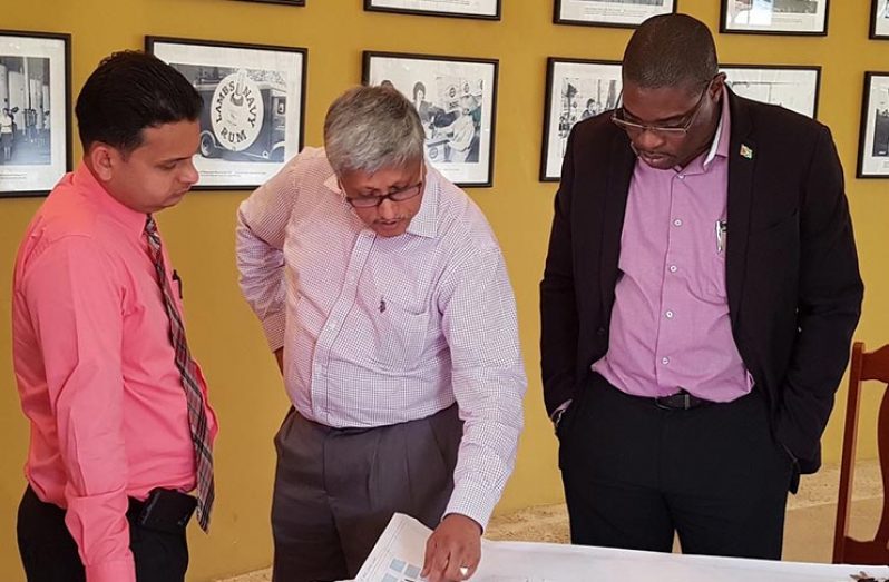 Minister of Public Infrastructure David Patterson, looks at a Diamond land-use map as DDL Chairman Komal Samaroo makes a point as DDL’s Finance Comptroller Vasuedo Sing looks on