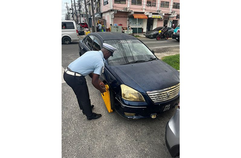 A rank of the GPF clamps a vehicle parked incorrectly on a street in Georgetown