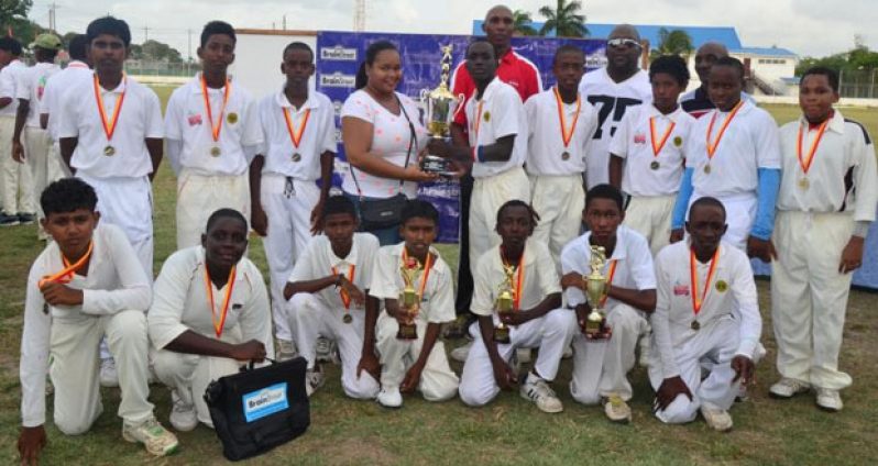 Yes we did it! The victorious Transport Sports Club Under-15 team strikes a pose with their spoils, even as their skipper Colin Barlow receives the GCA/BrainStreet Under-15 Cup from Mrs. Adrienne Harmon. (Photo by Adrian Narine)