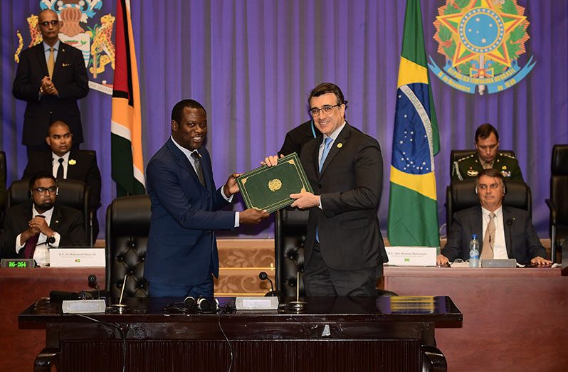 Minister of Foreign Affairs and International Co-operation, Hugh Todd and his Brazilian counterpart, Carlos França, hold one of two treaties that were signed to bolster legal co-operation between the two South American nations. The process was observed by the President of Guyana, Dr. Irfaan Ali and Brazil’s President, Jair Bolsonaro (Adrian Narine photo)