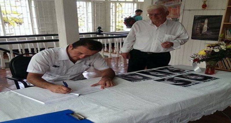 Deputy Head of Mission at the Mexican Embassy, Gabriel Ferrer appending his signature in the Book. Looking on at right is Pierre Saint-Arroman, Honorary Consul General for France to Guyana