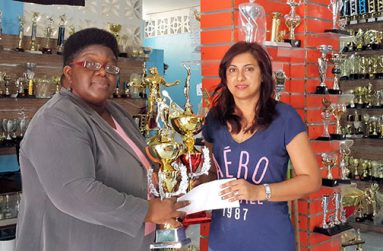Mrs. Devi Sunich (left), wife of the proprietor of Trophy Stall Ramesh Sunich, hands over the sponsorship cheque and symbolic partner trophies to president of the GTA Grace McCalman