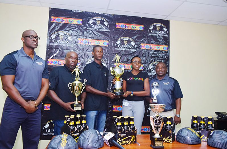One of the Colours/Guinness Greatest in the Street football West Demerara organisers collects the trophy from the Colours representative in the presence of Banks DIH executives. (Cullen Bess-Nelson photo)