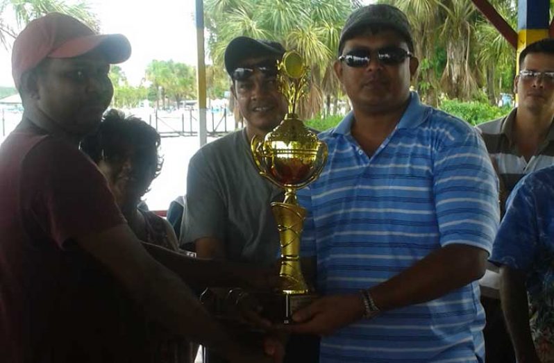 Travis Simon of Region 2 receives the winning trophy for the cricket competition from Regional Chairman Devanand Ramdatt.