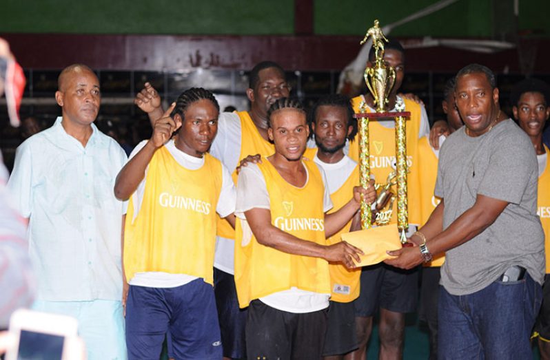 Banks DIH Outdoor Events, Manager Mortimer Stewart, hands over the first prize monies and winning trophy to Ol Skool Ballers captain, Roy Cassou, in the presence of teammates and Three Peat Promotions Co-Director, Rawle Welch,  Saturday night. (Delano Williams photos)