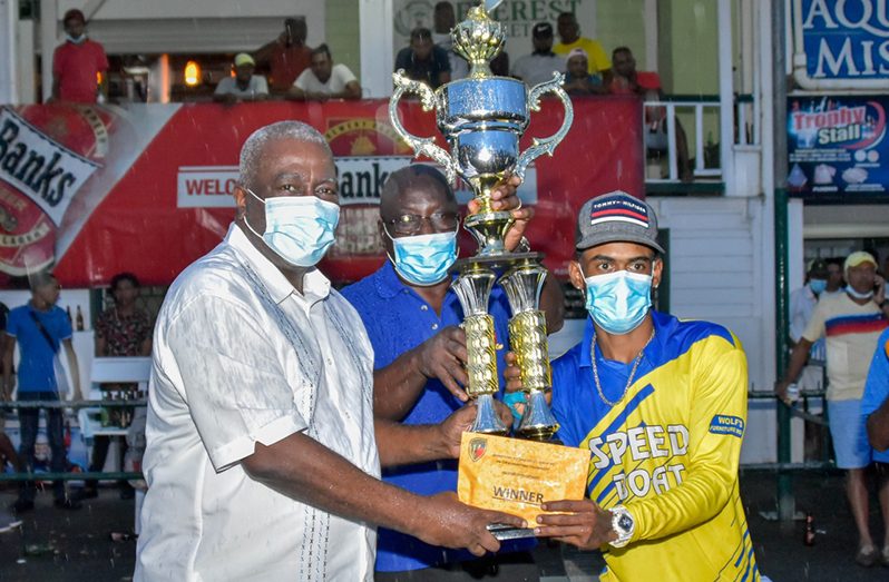 Prime Minister  Mark Phillips (Brigadier ret’d)  presents the Open trophy to Speedboat All Stars captain, Wazeer Hussain. At centre is Ian John , president of the Georgetown Softball Cricket League.