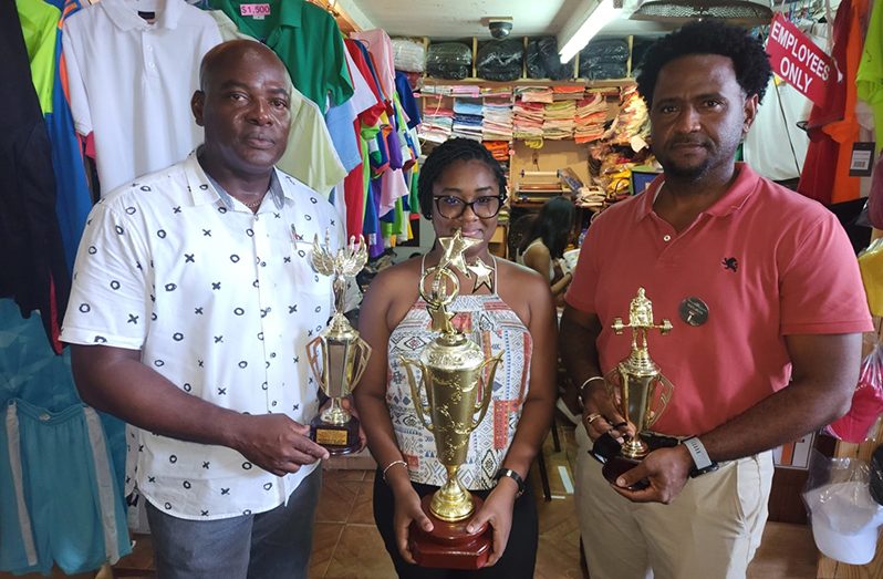 Ms. Tanya Crossman of the Trophy Stall, flanked by GAPLF’s Franklin Wilson (left) and Denroy Livan, displays some of the trophies.