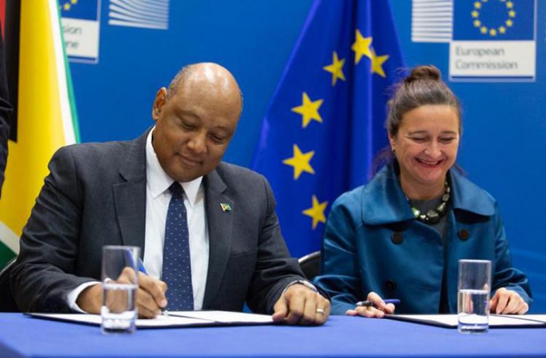 Minister of Natural Resources, Raphael Trotman signs onto a document to facilitate the legal trade of timber and timber products. (EU photo)