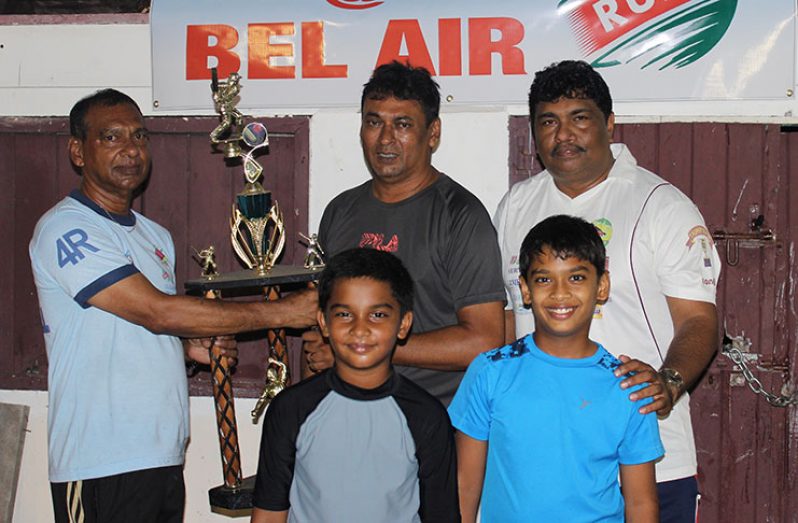 Ramesh Sunich of Trophy Stall (left) hands over the winners’ trophy to Anil Persaud of East Coast Cricket Committee in the presence of two Under-15 players and GFSCA representative Anil Beharry.