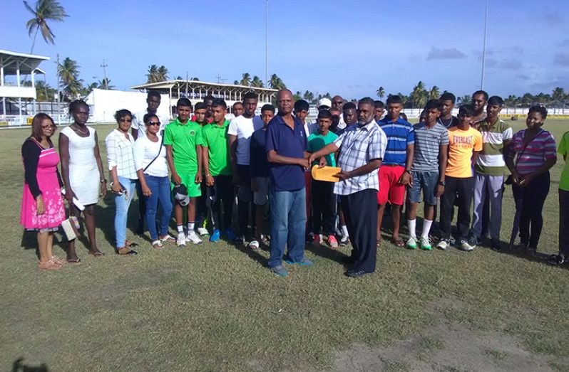 President of the Albion Cricket Club, Pastor Lloyd Kanden, hands over sponsorship to Berbice Cricket Board vice-president Albert Smith in the presence of cricketers and parents.