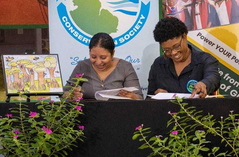 University of Guyana’s Vice-Chancellor, Professor Paloma Mohamed Martin (left) and Vice-Chairperson of the Guyana Marine Conservation Society (GMCS) Board of Directors, Dr. Arianne Harris, sign the Memorandum of Understanding at UG’s Education Lecture Theatre