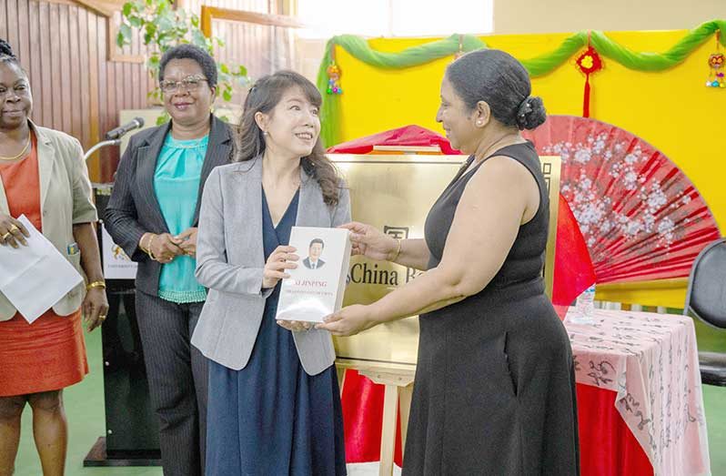 Chinese Ambassador Yang Yang presents one of the books donated, to Vice-Chancellor Paloma Mohamed-Martin