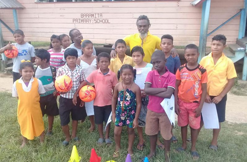 Coach Gordon Brathwaite poses with some of the young footballers of the Baramita Primary School.