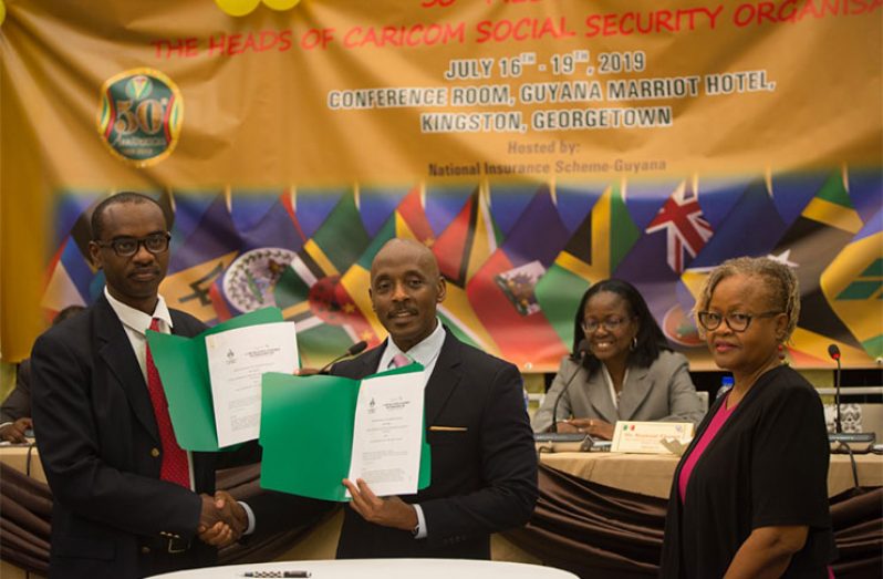 Director of the Inter American Centre for Social Security Studies, Reginald Thomas (right), and Dean of the Faculty of Social Sciences for UWI’s Cave Hill Campus, Justin Robinson, after signing the MoU