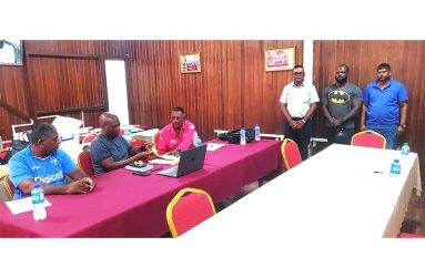 Umpire Dharam Singh, Tejram Baldeo, and Heathcliff Peters (Standing)