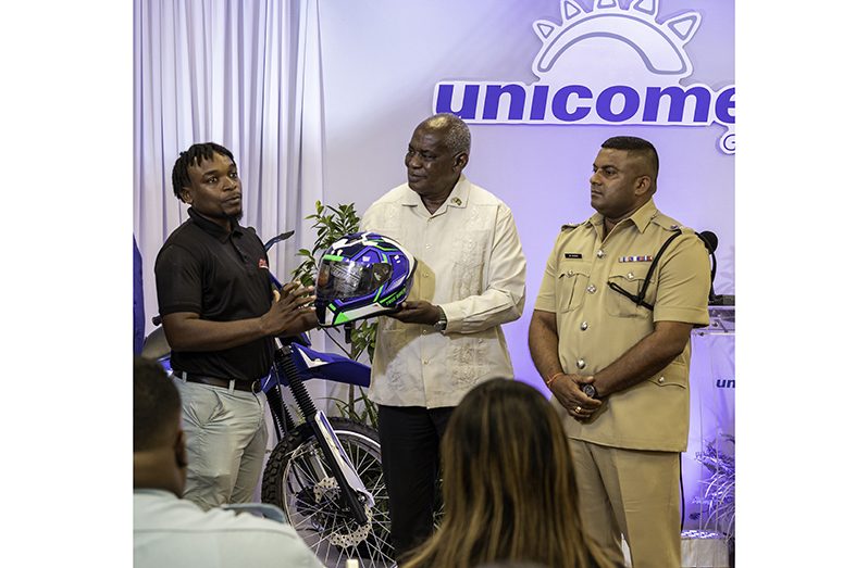 Minister of Home Affairs, Robeson Benn and Traffic Chief, Mahendra Singh, receive a donation from Unicomer - Courts Guyana Brand Manager Collis Venture (left)