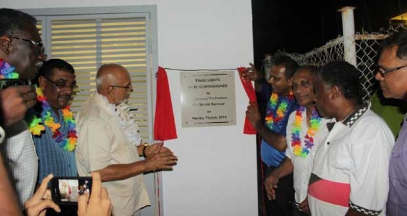 With the help of Minister of Culture, Youth and Sport, Dr. Frank Anthony (right), President Donald Ramotar proudly unveils the plaque to symbolise the commissioning of the newly-installed lights at the Albion Community Centre ground on Monday