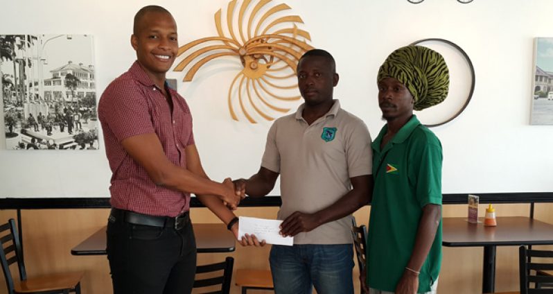 CEO of German’s Restaurant, Clinton Urling (left), presents cheque to the president of Dolphin’s Club, Paul Mahaica (centre), while another club representative looks on.