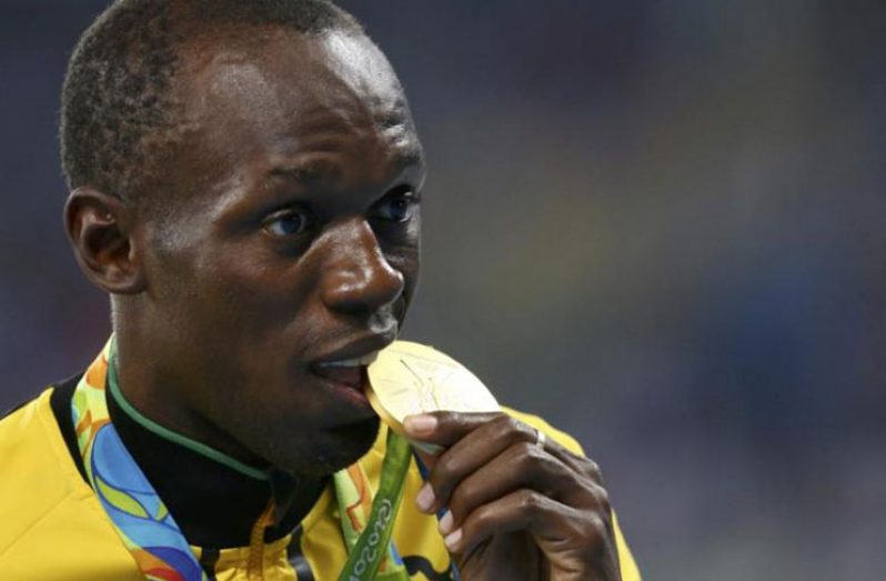 Gold medallist Usain Bolt of Jamaica bites his medal. (REUTERS/Alessandro Bianchi)