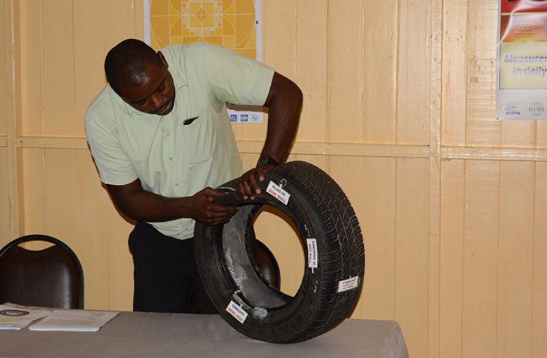 Senior Inspector for Legal Metrology and Standards Compliance, Dillon Beckles, inspects a used tyre
