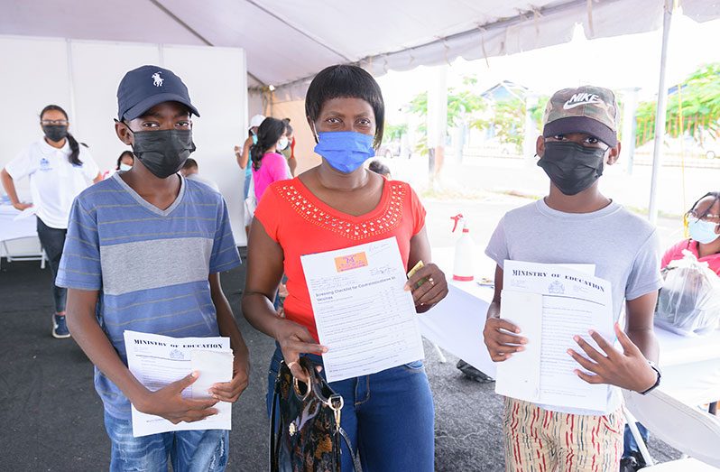 Jillian Hinds and her two sons showing their COVID-19 vaccination forms while at the COVID-19 vaccination drive-thru site at the Guyana National Stadium, on Saturday